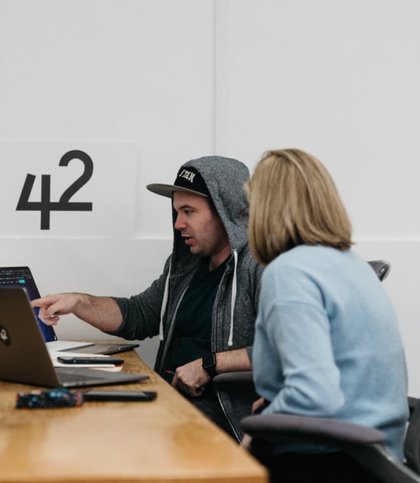 Two 42 team members working together at a laptop